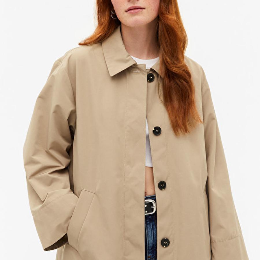 A female model wearing a beige trench coat